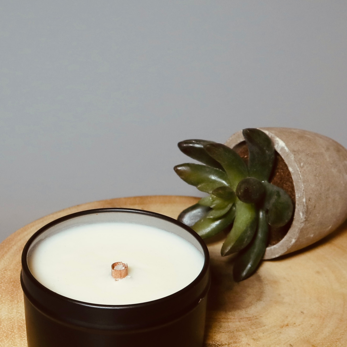 Cinnamon tube wick candle display on a wooden board in a lovely black travel tin