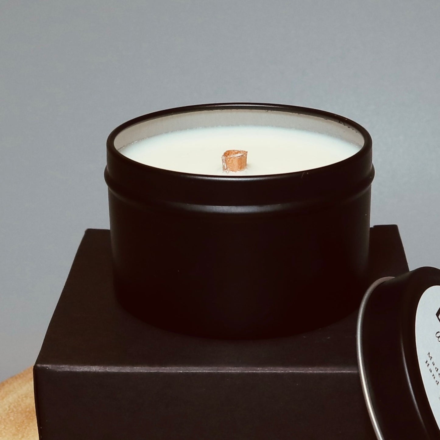 travel candle display in a black tin sitting on on black gift box