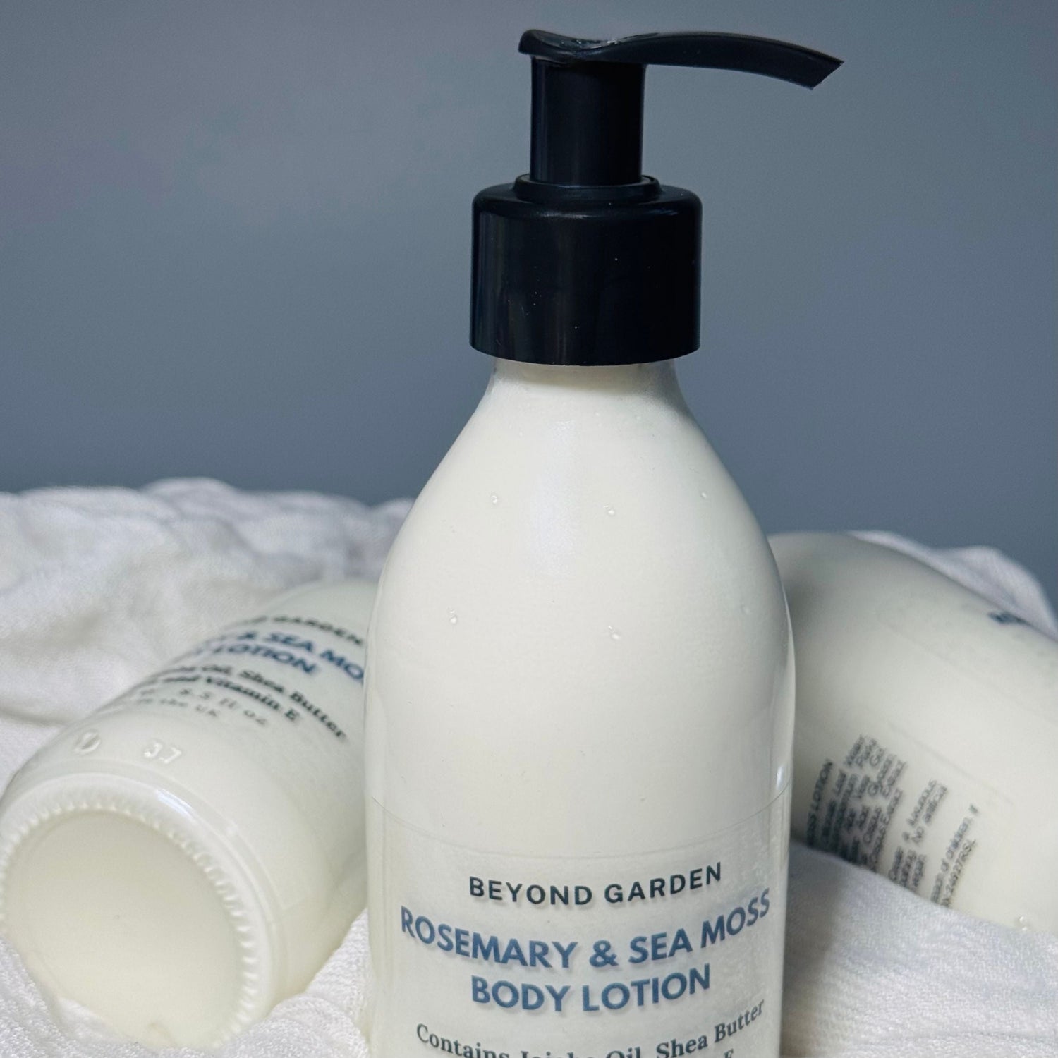 Body Lotion in a pump bottle, surrounded by additional bottles on a soft white fabric, showcasing a creamy, hydrating lotion