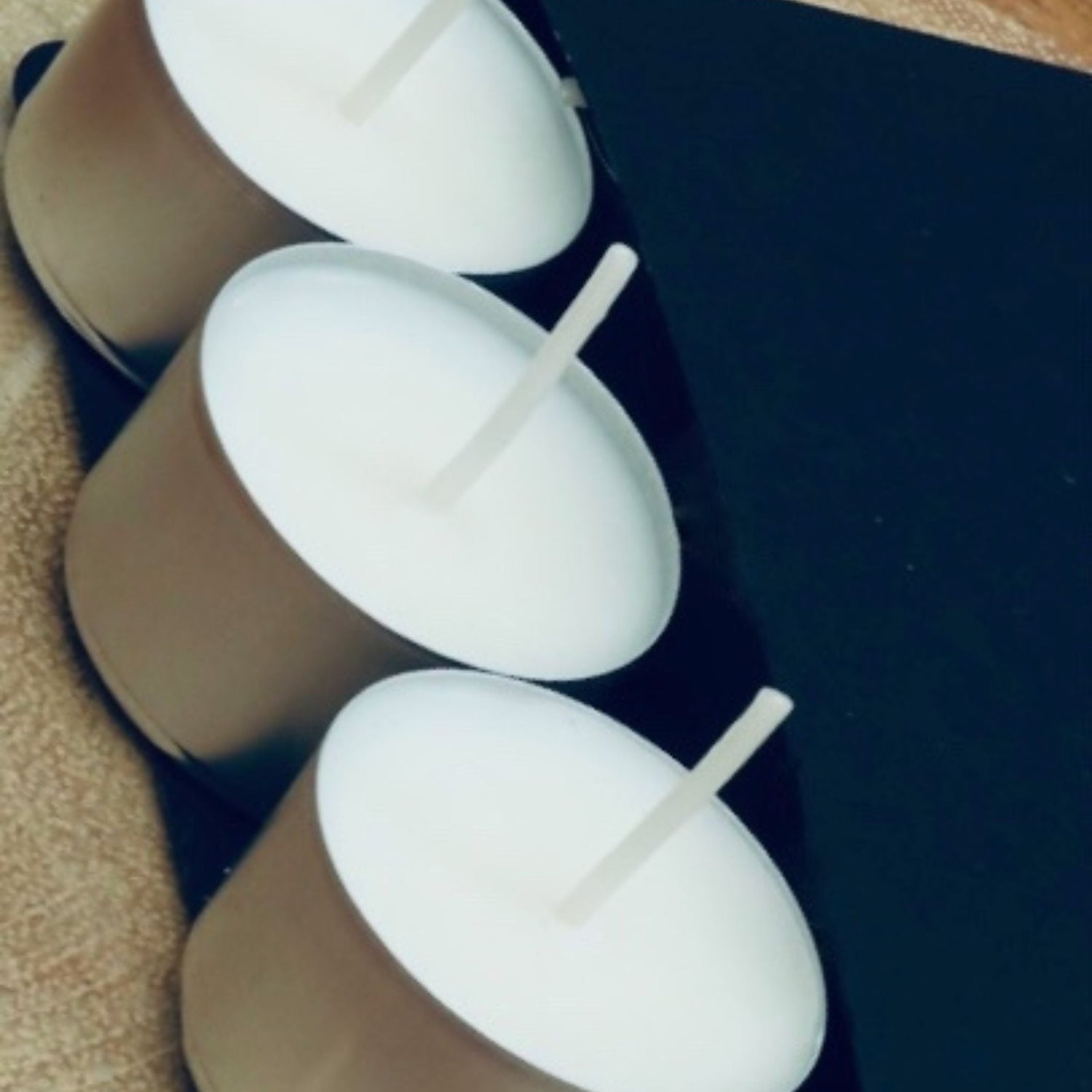 white soy tea light in silver container display next to a black box